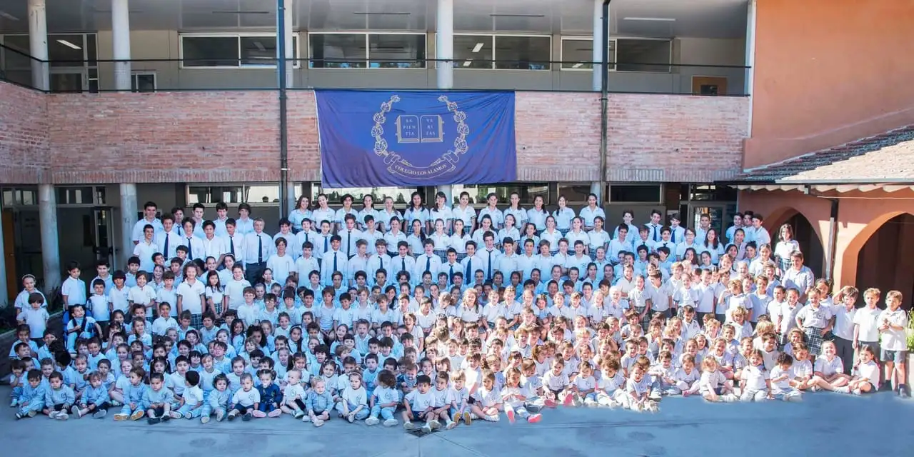 Todos los alumnos del colegio, de maternal a secundario, reunidos en el patio central bajo la bandera con el escudo institucional