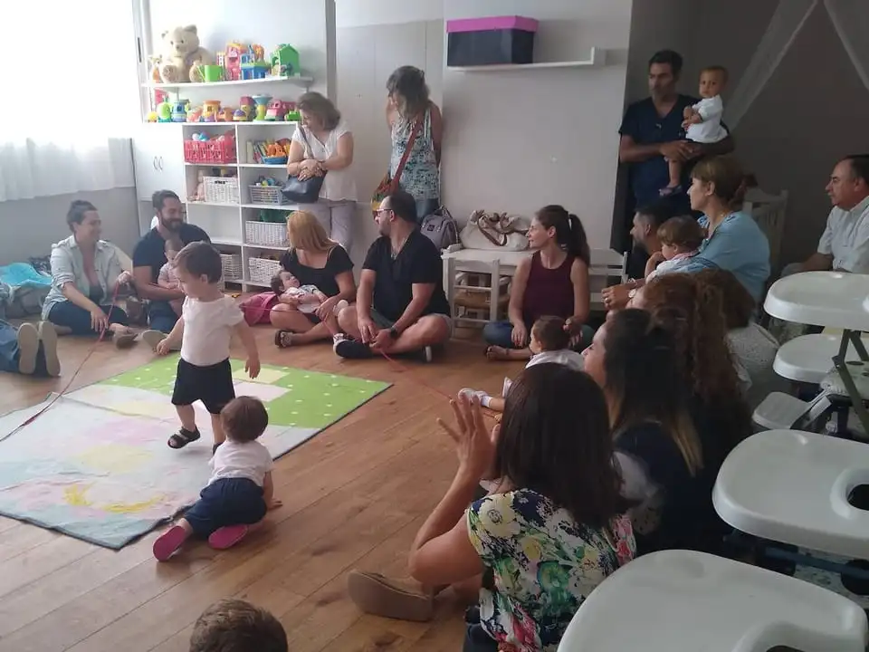Familias y bebés compartiendo una actividad de juego en la sala de maternal